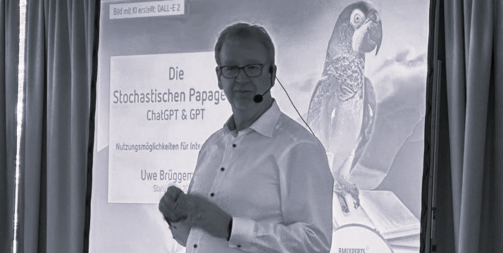 Keynote Vortrag ChatGPT - Keynotespeaker Uwe Brüggemann steht vor einem Bild, wo steht: Die stochastische Papageien